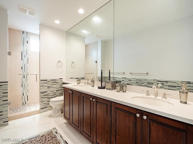 bathroom featuring a tile shower, vanity, tile walls, tile patterned flooring, and toilet