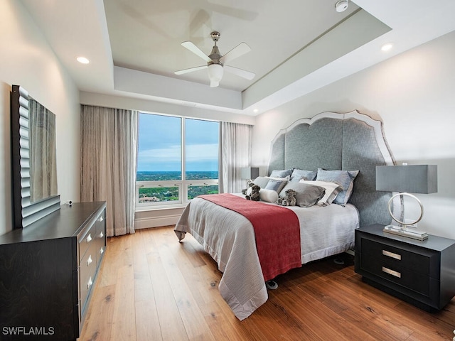 bedroom featuring a raised ceiling, ceiling fan, and dark hardwood / wood-style floors