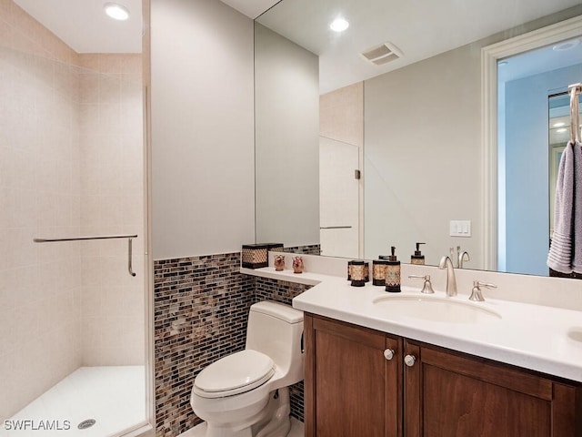 bathroom featuring walk in shower, vanity, toilet, and tile walls