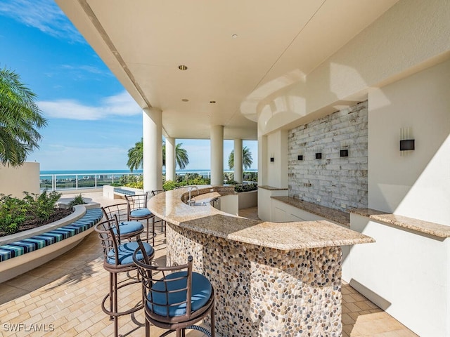 view of patio featuring a water view and exterior bar