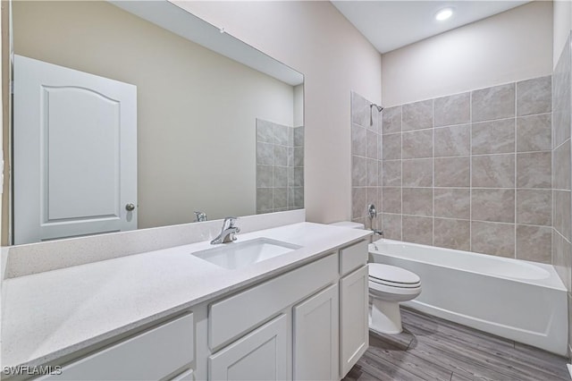 full bathroom featuring toilet, vanity, tiled shower / bath combo, and hardwood / wood-style flooring