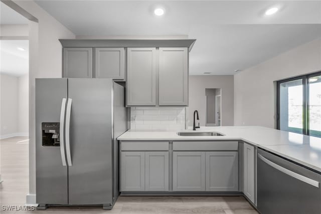 kitchen featuring appliances with stainless steel finishes, gray cabinetry, a sink, light countertops, and recessed lighting