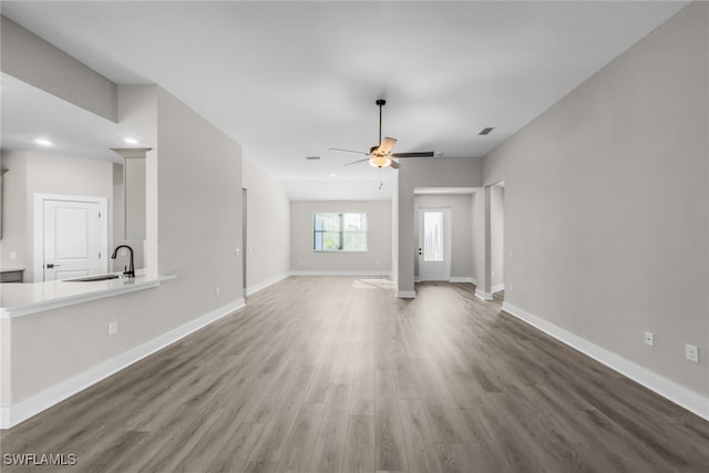 unfurnished living room with a sink, ceiling fan, wood finished floors, baseboards, and recessed lighting