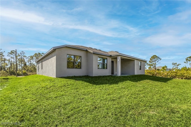 rear view of property with a lawn and stucco siding