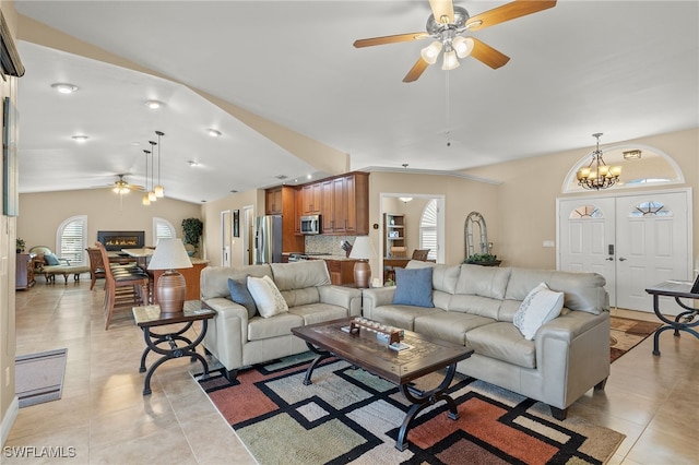 tiled living room with lofted ceiling and ceiling fan with notable chandelier