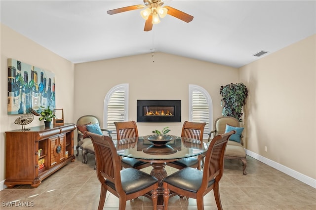 dining space with ceiling fan, light tile patterned flooring, a healthy amount of sunlight, and vaulted ceiling