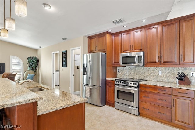 kitchen with appliances with stainless steel finishes, decorative light fixtures, light stone countertops, and sink