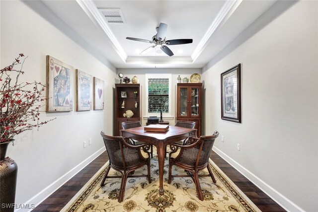 dining space featuring ceiling fan, ornamental molding, wood-type flooring, and a raised ceiling