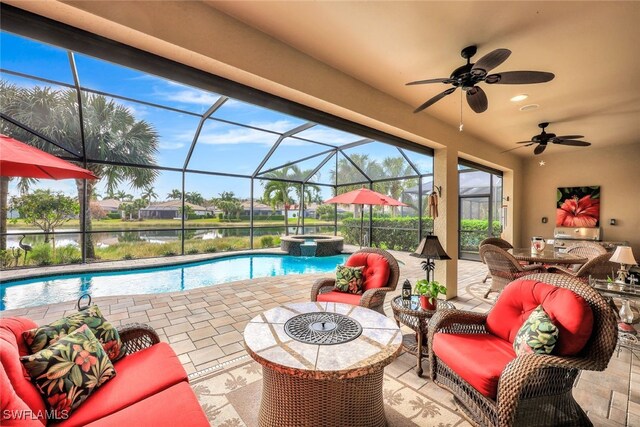 view of pool featuring a patio, an in ground hot tub, ceiling fan, glass enclosure, and a water view