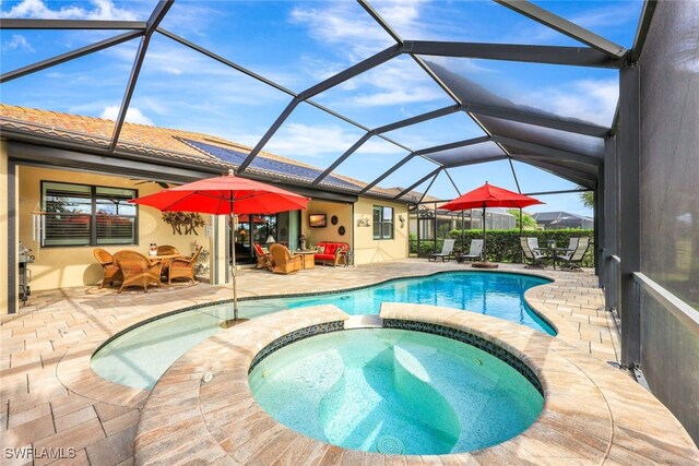 view of pool with an in ground hot tub, a patio area, and glass enclosure