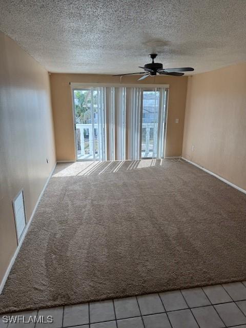 unfurnished room featuring ceiling fan, light carpet, and a textured ceiling