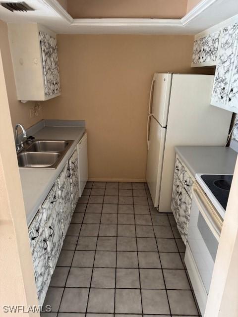 kitchen with tile patterned floors, sink, white cabinets, and white appliances