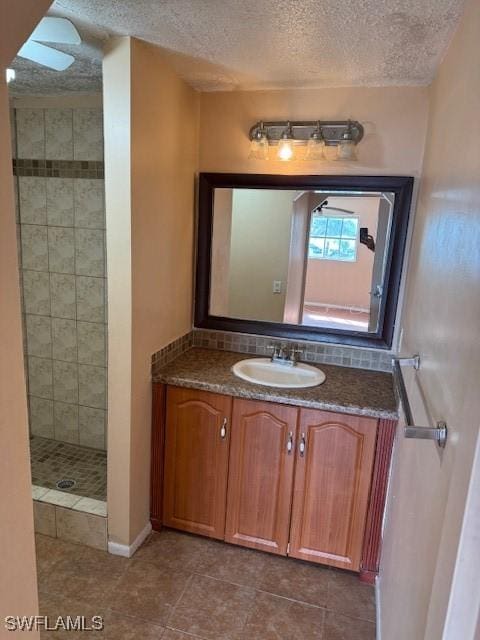 bathroom featuring tiled shower and vanity