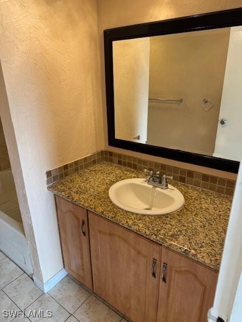 bathroom with backsplash, a bathing tub, tile patterned floors, and vanity