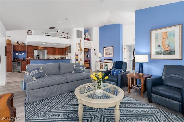 living room with high vaulted ceiling, light hardwood / wood-style floors, and wine cooler