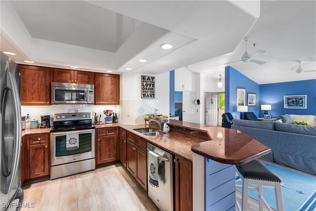 kitchen featuring kitchen peninsula, appliances with stainless steel finishes, a kitchen bar, and sink