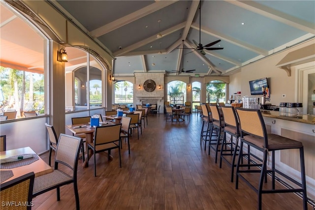 dining space with vaulted ceiling with beams, ceiling fan, a fireplace, and plenty of natural light