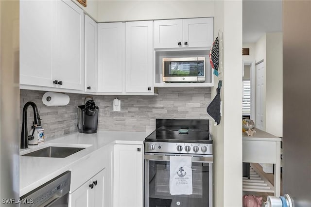 kitchen with white cabinets, backsplash, stainless steel appliances, and sink