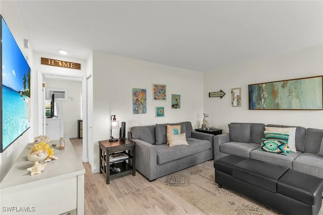 living room featuring an AC wall unit and light hardwood / wood-style floors