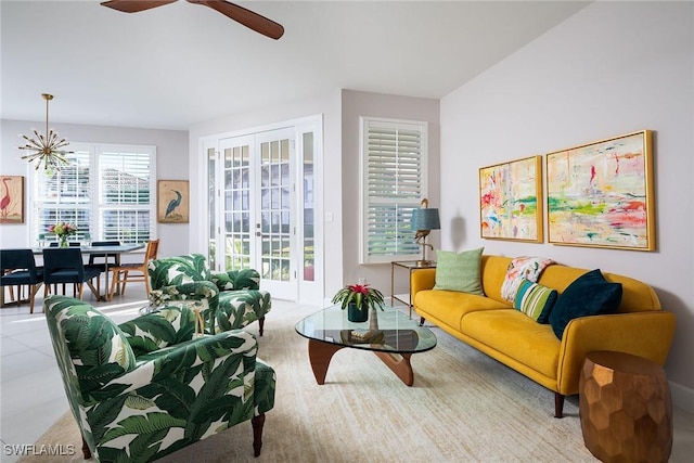 living room featuring ceiling fan with notable chandelier and french doors