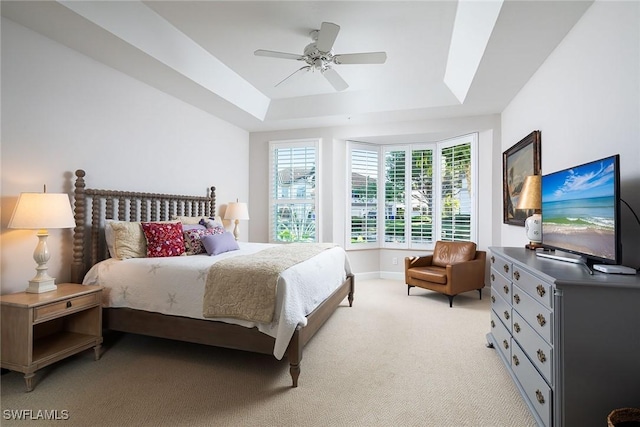 bedroom featuring light colored carpet, ceiling fan, and a tray ceiling