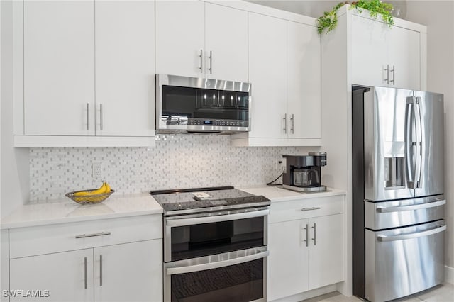 kitchen featuring white cabinetry, backsplash, light stone countertops, and appliances with stainless steel finishes