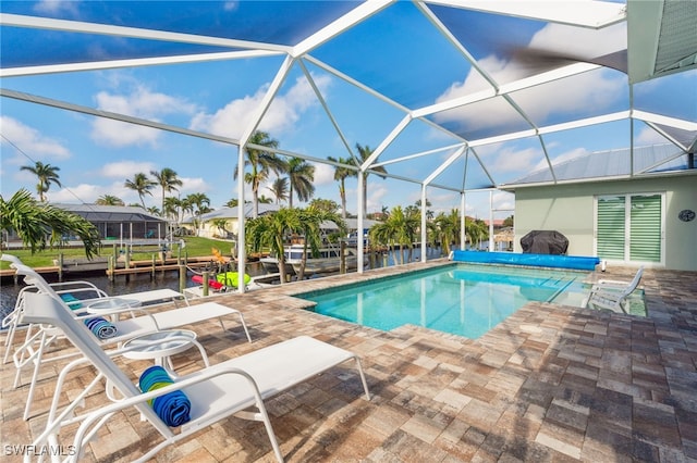 view of pool featuring grilling area, a patio area, a water view, and glass enclosure