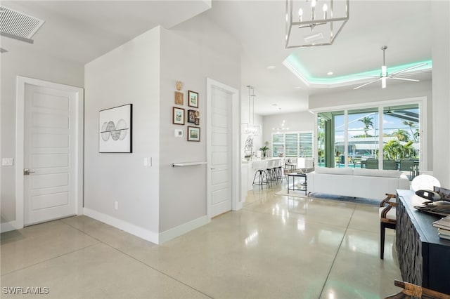 hall with concrete flooring and an inviting chandelier