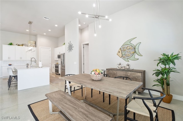 dining room featuring sink, a towering ceiling, and a chandelier