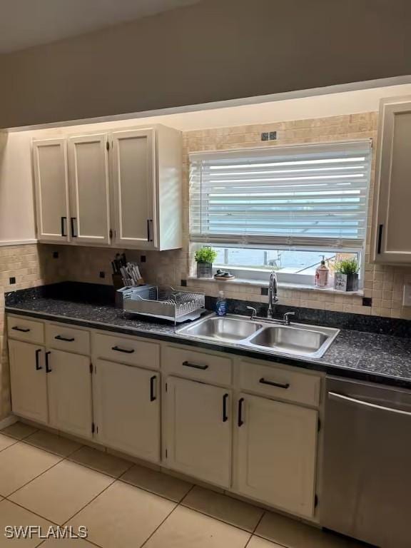 kitchen featuring light tile patterned floors, white cabinetry, stainless steel dishwasher, and sink