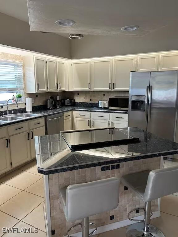 kitchen featuring sink, stainless steel appliances, a kitchen island, a kitchen breakfast bar, and light tile patterned floors