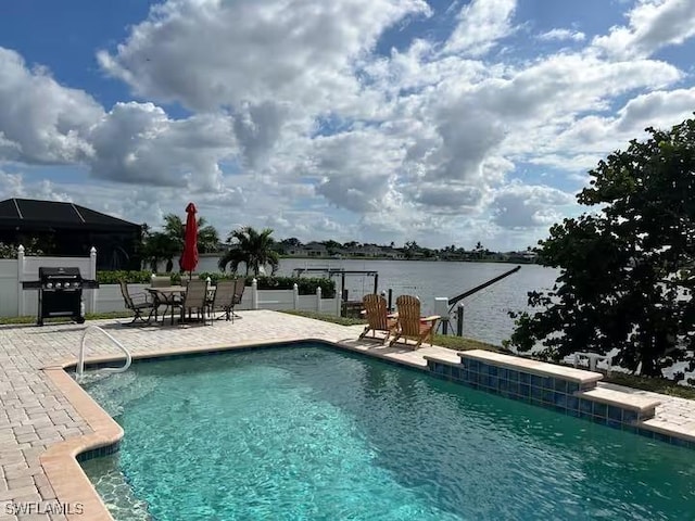 view of pool with a grill, a water view, and a patio