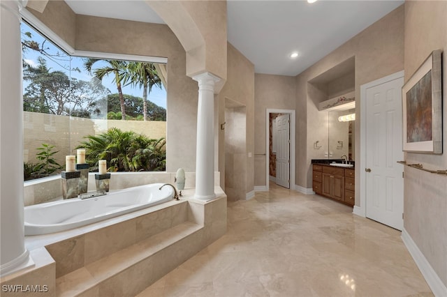 bathroom with vanity, a relaxing tiled tub, and ornate columns