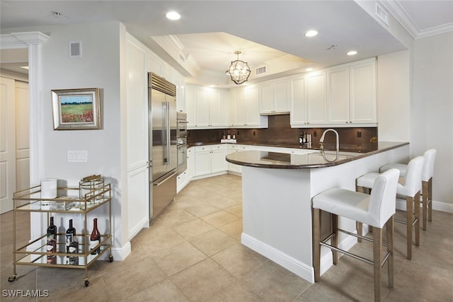 23850 Via Italia Cir Unit 406, Estero, FL 34134 - kitchen featuring a tray ceiling, stainless steel built in fridge, a peninsula, ornamental molding, and visible vents