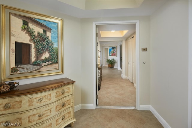 hallway featuring a raised ceiling and light tile patterned floors