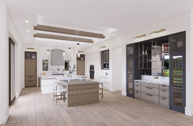 kitchen with a breakfast bar area, a large island, double wall oven, and light wood-type flooring