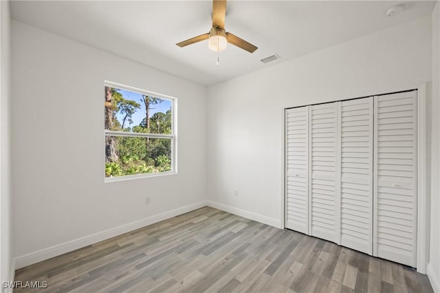 unfurnished bedroom featuring ceiling fan, a closet, and light hardwood / wood-style floors