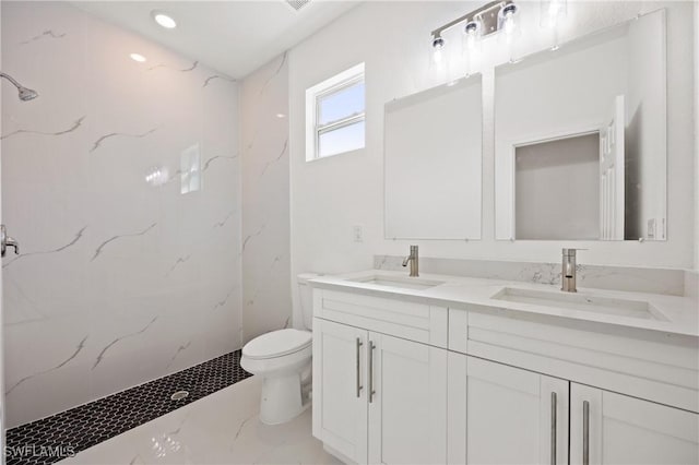 bathroom with vanity, toilet, and tiled shower