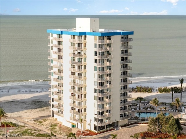 view of building exterior with a beach view and a water view