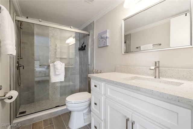 bathroom with vanity, toilet, a shower with shower door, and ornamental molding