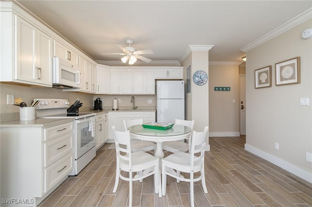 kitchen with ceiling fan, sink, crown molding, white appliances, and white cabinets