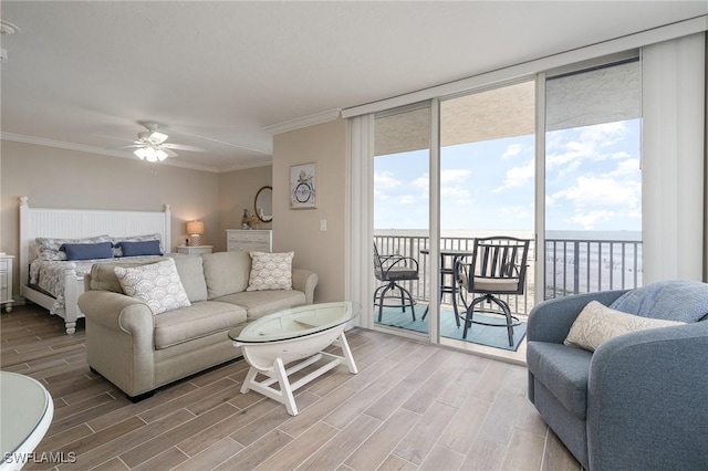 living room featuring ceiling fan, expansive windows, a water view, and crown molding