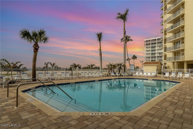 pool at dusk featuring a patio area