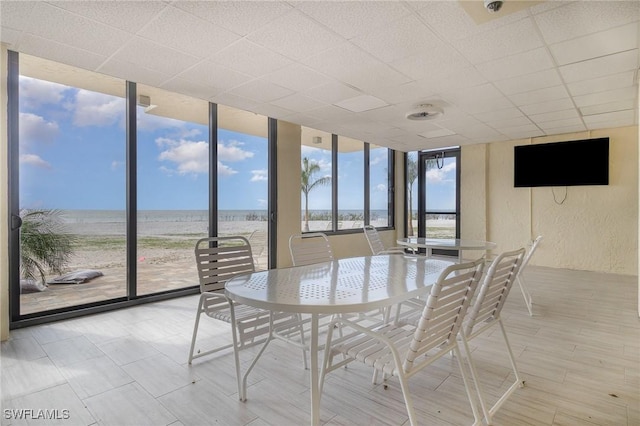 unfurnished sunroom featuring a water view and a view of the beach