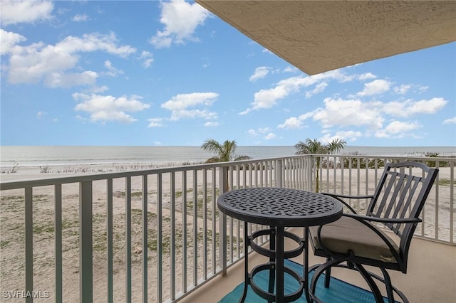 balcony with a water view and a view of the beach