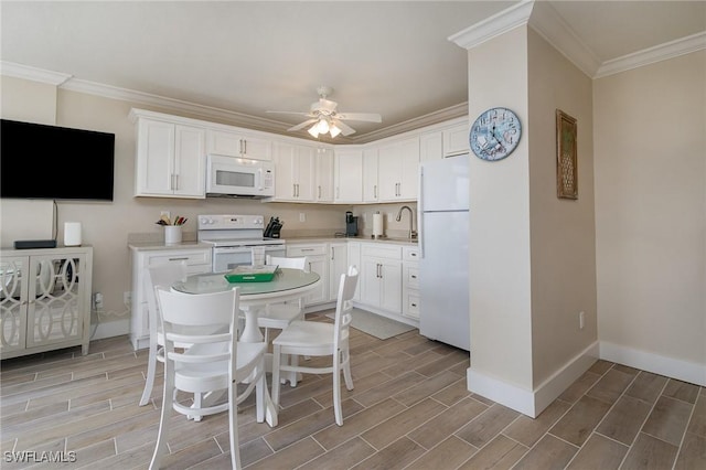 kitchen with ceiling fan, white appliances, a kitchen bar, white cabinets, and ornamental molding