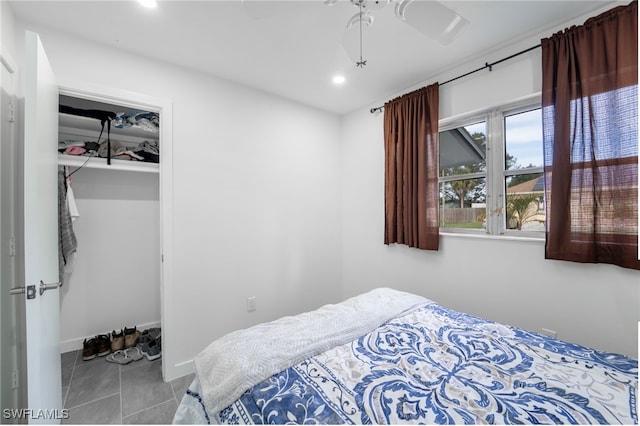 tiled bedroom with ceiling fan and a closet