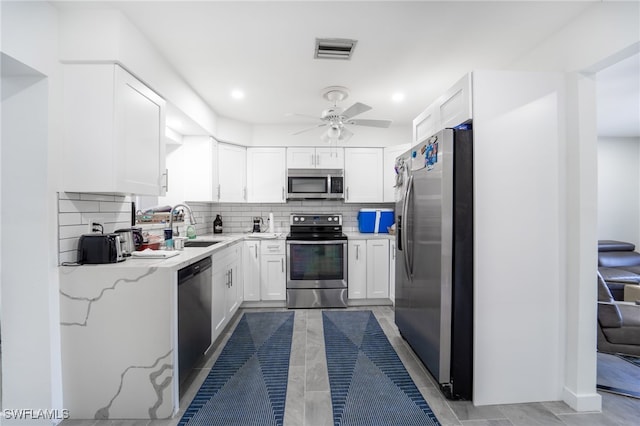 kitchen with sink, ceiling fan, appliances with stainless steel finishes, tasteful backsplash, and white cabinetry