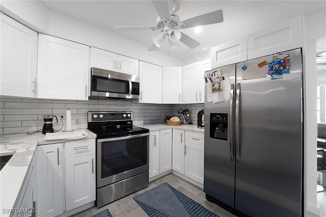 kitchen featuring decorative backsplash, white cabinetry, light stone countertops, and appliances with stainless steel finishes