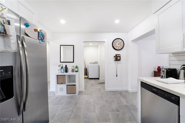 kitchen with appliances with stainless steel finishes, white cabinetry, and washer / dryer